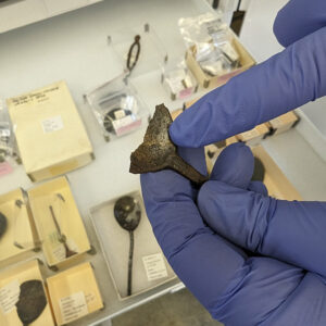 Senior Curator Leah Stricker points to an unidentified maker's mark in the bowl of a fragmented spoon.