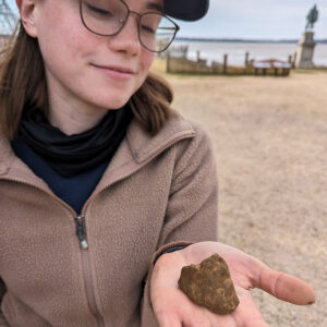 Staff Archaeologist Natalie Reid holds an animal hoof found in the Church Tower excavations.