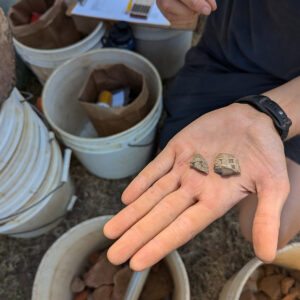 Two sherds of a pipe bowl bearing a steam locomotive found in front of the Archaearium.