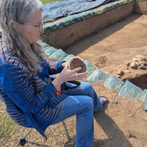 Director of the Voorhees Archaearium Archaeology Museum Jamie May examines a wine bottle found in the 1607 Burial Ground. The bottle is likely related to a series of late 17th-century wine bottles found in a nearby cellar in 2004. Jamie was one of the archaeologists who excavated that feature over two decades ago.