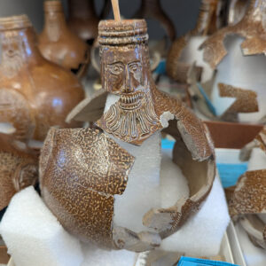 A partial Bartmann jug rests on a foam support created by Assistant Conservator Jo Hoppe as she mends it together.