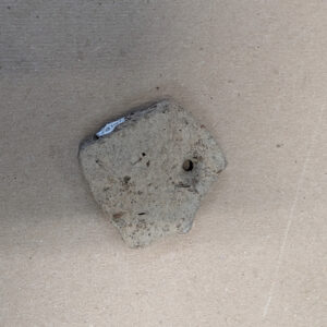 A sherd of Native ceramic among those being examined by curatorial intern Molly Morgan. This one contains a drilled hole.