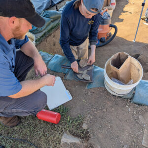Director of Archaeology Sean Romo and Staff Archaeologist Natalie Reid examine the wine bottle found in the 1607 Burial Ground excavations.