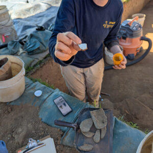 Staff Archaeologist Natalie Reid holds a sherd of delftware she found while excavating in the 1607 Burial Ground.