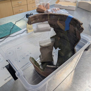 Assistant Conservator Jo Hoppe uses bags of sand and painter's tape to stabilize the LPMR jar while a mended section's adhesive solidifies.