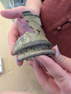 Assistant Curator Lauren Stephens holds a refined red bodied earthenware vessel that she's mending. The vessel was manufactured between 1800 and 1850 and was found just south of the Archaearium.