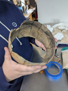 Assistant Conservator Jo Hoppe holds the Yeocomico Scraped ceramic jar she is mending. She discovered that some of its mends were coming apart during an inspection of the Archaearium.