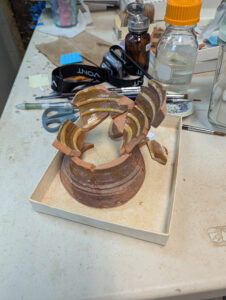 The chafing dish being mended by Assistant Curator Lauren Stephens