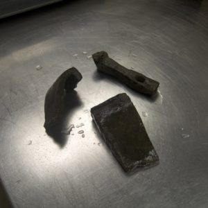iron axe blade fragment, hammer, and wedge on a lab table