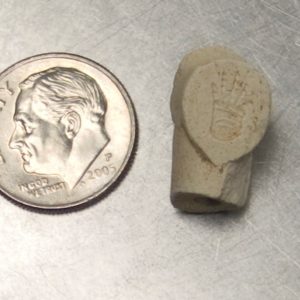 Pipe heel fragment next to a dime for scale