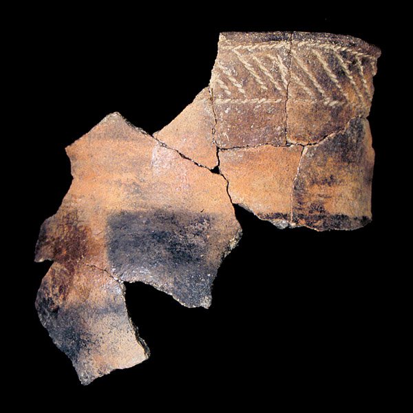 Mended sherds of an earthenware pot with horizontal line decoration around rim