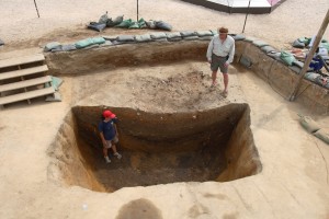 Archaeologists stand around deep excavation unit