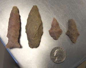 Projectile points next to a quarter for scale