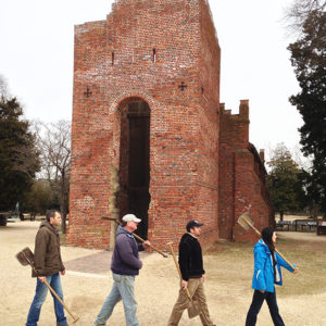 Four archaeologists walking in front of brick church tower