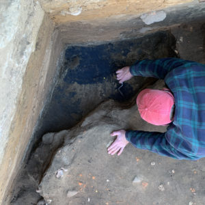 archaeologist troweling in the corner of a unit