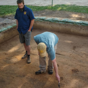 Two archaeologists stand in excavation unit