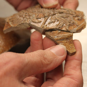 Hand fitting stoneware sherd to two previously-mended sherds