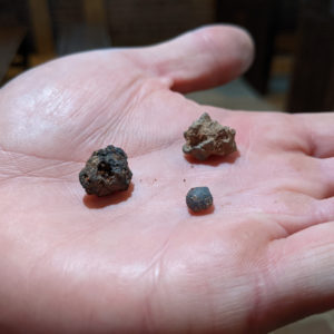 hand holding three small pieces of slag
