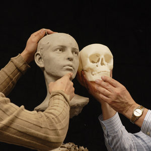 Facial reconstruction held next to skull model