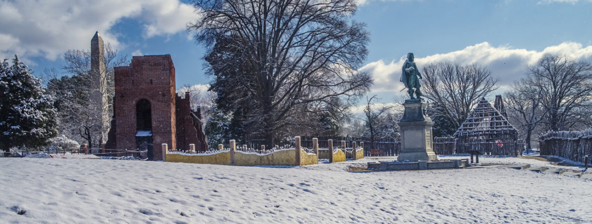 brick church, low wall, statue, wooden building frame, and palisade covered in snow