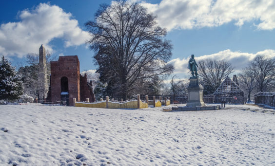 brick church, low wall, statue, wooden building frame, and palisade covered in snow