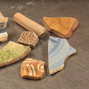 variety of ceramic sherds and pipe stem fragments on a table
