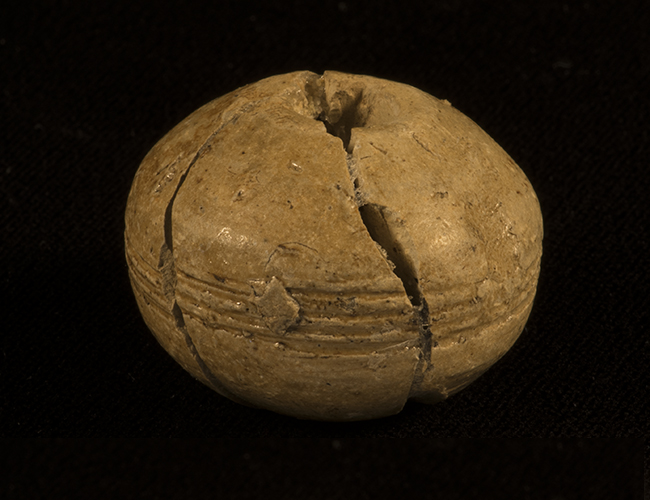 Small round earthenware spindle whorl with hole in the middle