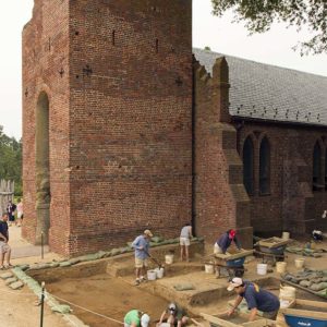 group of archaeologists excavating in front of a brick church