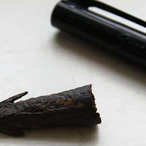 Crossbow bolt fragment next to a pen tip for scale