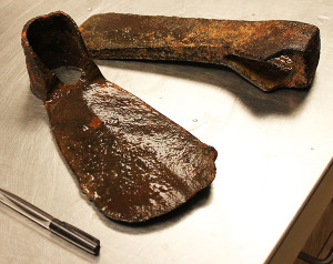 Corroded hoe blade and axe head on a lab table