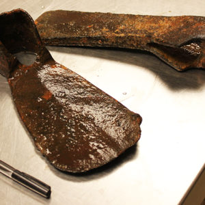 Corroded hoe blade and axe head on a lab table