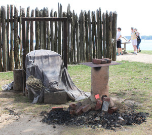 Small recreated iron bloomery in front of a palisade