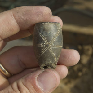 Hand holding a pipe bowl fragment decorated with a stippled star