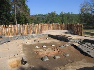 Excavation unit lined with sandbags in front of a palisade