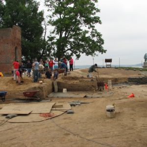 A group of archaeologists and visitors gather at the side of excavations