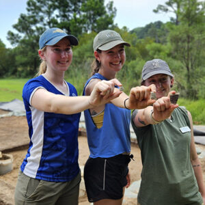 Field school students attending William & Mary (Janne Wagner, Lianna Styles, and Ren Willis) hold sherds of the Mary II Westerwald jug. William & Mary was named in honor of Mary and her husband King William III.