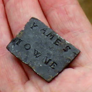 Hand holding square lead shipping tag stamped "Yames Towne"