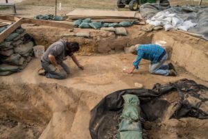 Archaeaologists excavating in unit lined with sandbags