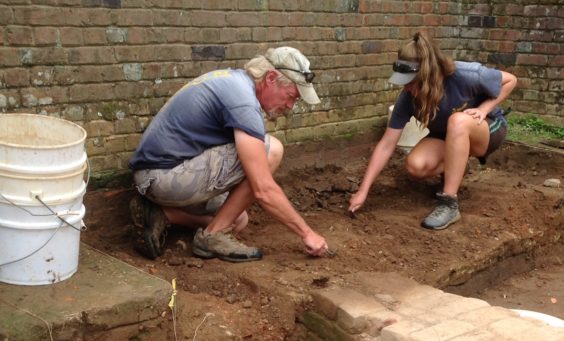 Archaeologists excavating by a brick church