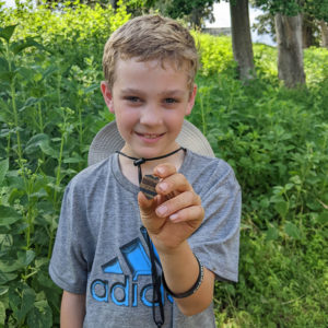 A camper holds a sherd of delftware he found while screening.