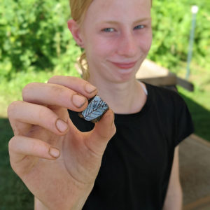 A camper holds a sherd of delftware she found while screening.