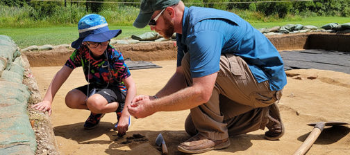 Senior Staff Archaeologist Sean Romo instructs a camper on the troweling process.
