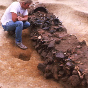 Archaeologist Kevin Goodrich examines artifacts found in the Bacon's Castle trash pit in the mid-1980s. The cauldron can be seen near the rear of the photo.