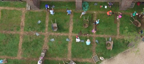 Aerial view of wheelbarrows and students shoveling in square excavation units