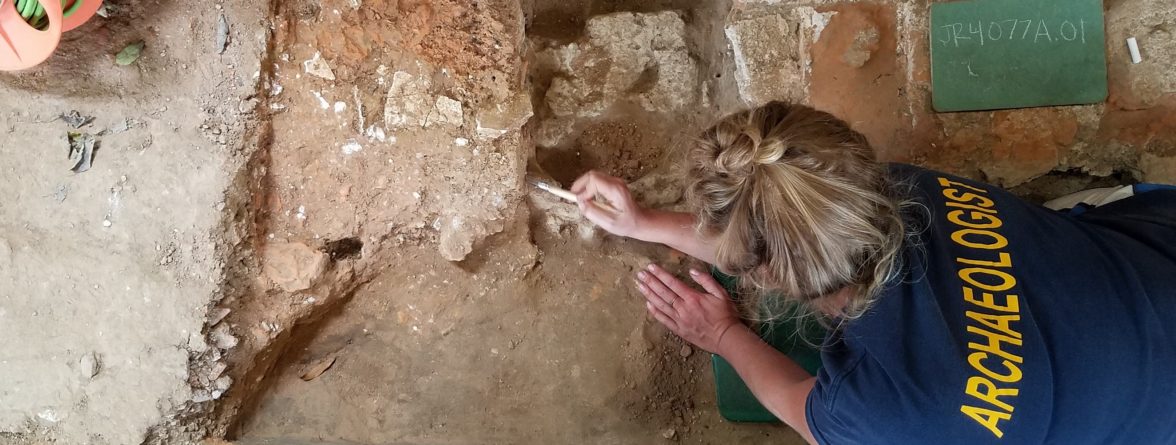 Archaeologist excavating floor features