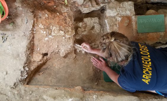 Archaeologist excavating floor features