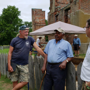 Group talks in front of fence and brick ruins