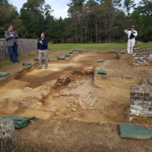 Archaeologists stand in excavation unit