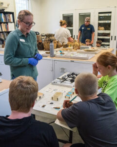 Associate Curator Janene Johnston shares artifacts with camp attendees.